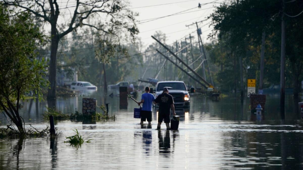 People walk up a street flooded in the aftermath of Hurricane Ida in Jean Lafitte, Louisiana. — AP