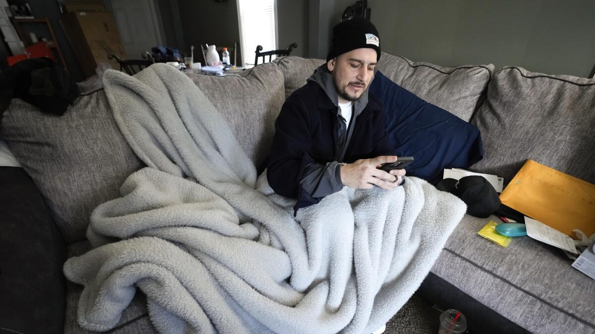 Mitch Wengrzynowicz sits under a blanket as his home lost power in Dearborn, Michigan on Friday. — AP