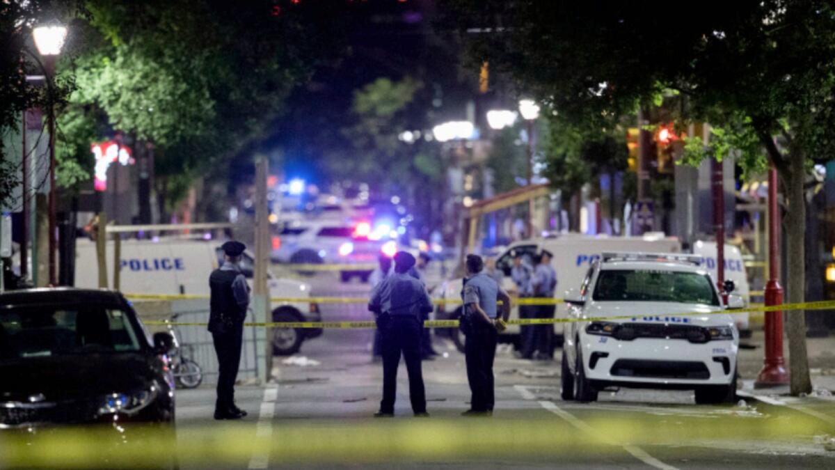 Philadelphia Police officers and detectives look over evidence at the scene of a shooting in Philadelphia. — AP