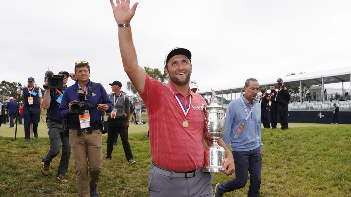 Jon Rahm of Spain celebrates with the trophy as he leaves the trophy ceremony after winning the US Open. — AFP