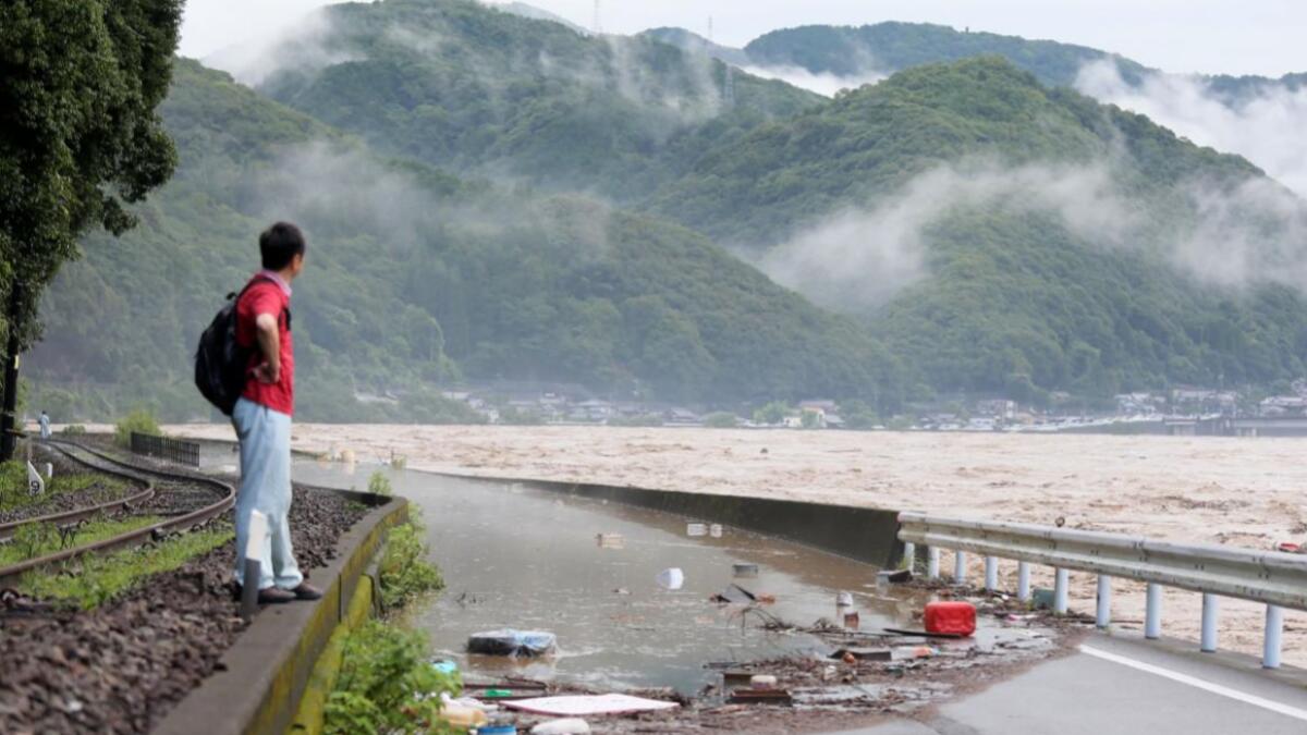 A man looks at the overflowing kuma river caused by heavy rain in Yatsushiro, Kumamoto prefecture. Some 75,000 people were ordered to evacuate in western Japan on July 4 as record heavy rain triggered floods and landslides, local media and officials said. The nation's weather agency issued the highest level of heavy rain warnings to Kumamoto and Kagoshima on Kyushu island.  Photo: AFP
