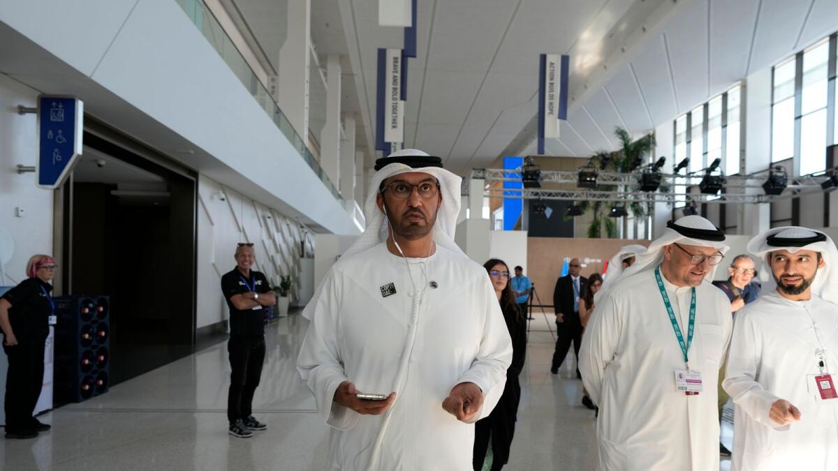 Dr Sultan Al Jaber wears headphones as he walks though the COP28 UN Climate Summit in Dubai. — AP