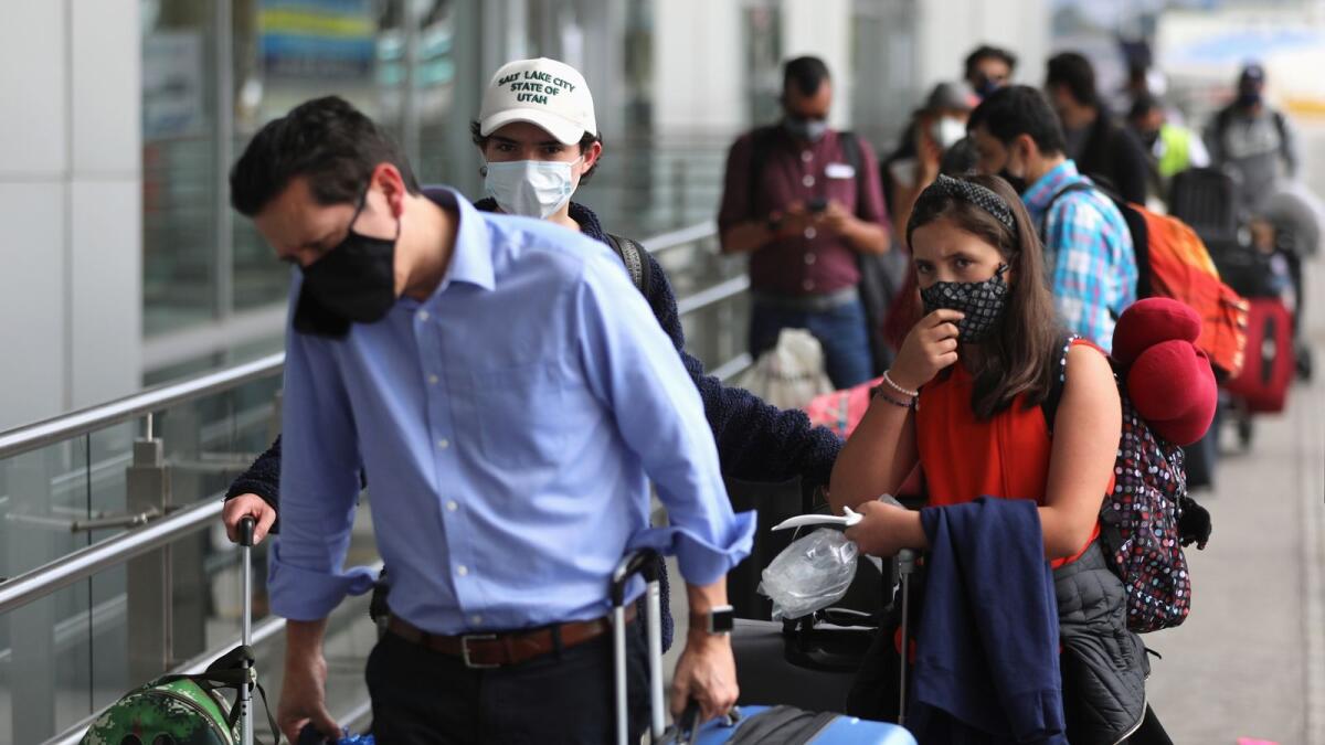 Passengers wearing face masks line up to check in at El Dorado airport.