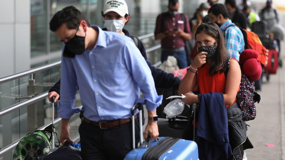 Passengers wearing face masks line up to check in at El Dorado airport.