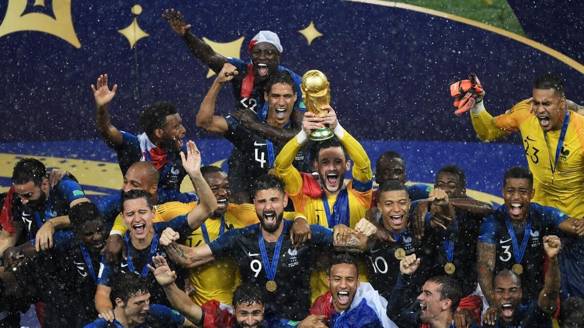 France's goalkeeper Hugo Lloris (centre) holds the trophy next to Olivier Giroud (right) and Kylian Mbappe as they celebrate with teammates during the trophy ceremony (AFP)