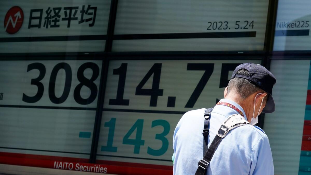 A person stands in front of an electronic stock board showing Japan's Nikkei 225 index at a securities firm Wednesday in Tokyo. Asian stock markets slid Wednesday as the US government crept closer to a potentially disruptive default on its debt. — AP