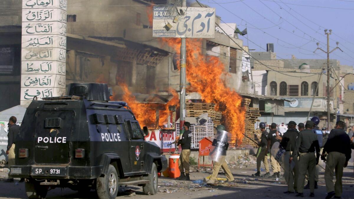 Police officers arrive to confront angry supporters of Tehreek-e-Labiak Pakistan, who set fires during protests following the arrest of their party leader Saad Rizvi, in Karachi. — AP