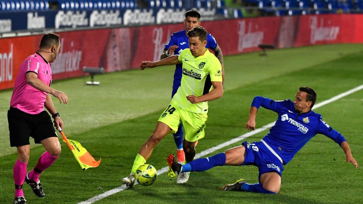 Atletico Madrid's Spanish midfielder Marcos Llorente is tackled by Getafe's Uruguayan midfielder Mauro Arambarri. — AFP