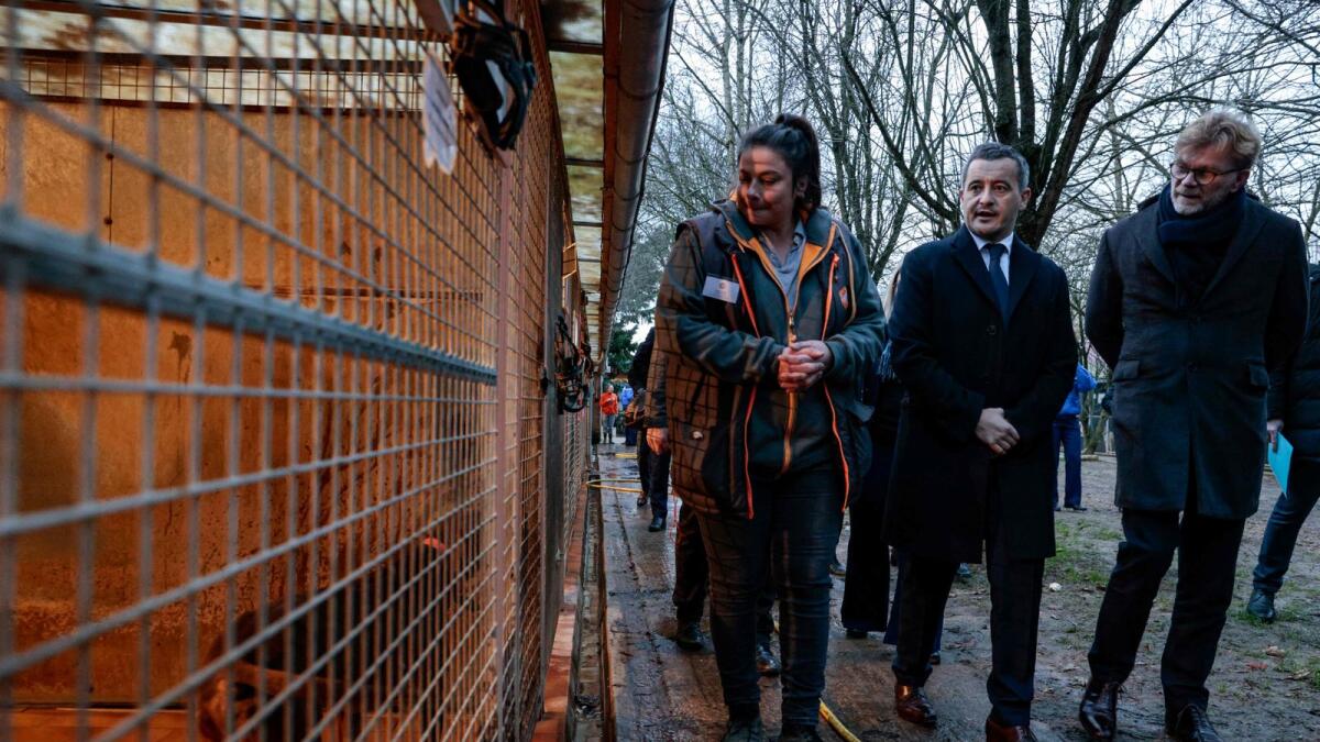 France's Interior Minister Gerald Darmanin speaks with SPA staff member, Olivia (L) as they inspect animal cages during a visit at the 'SPA de Chamande' animal shelter in Chamande, south of Paris, on Friday. — AFP