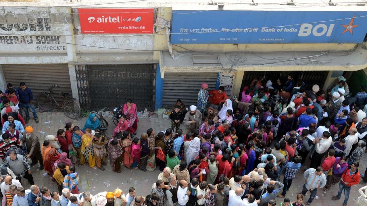People queue outside a bank as they wait to deposit and exchange 500 and 1000 rupee notes