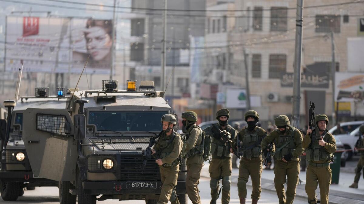 Israeli soldiers take up positions at the scene of a Palestinian shooting attack on an Israeli car at the Hawara checkpoint, near the West Bank city of Nablus. — AP