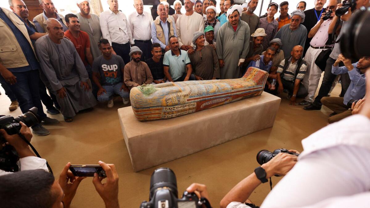 Mostafa Waziri, secretary-general of Egypt's Supreme Council of Antiquities takes a souvenir picture with the official archaeologists' team in front of a sarcophagus found at the newly discovered site. — Reuters