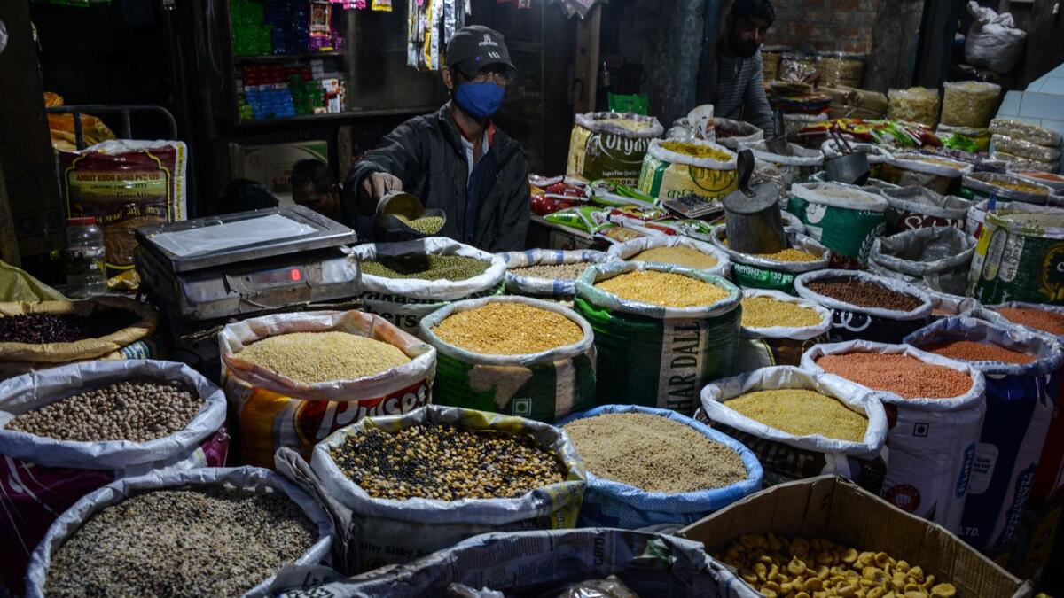 A vendor weighs pulses at his stall in a market in Siliguri - AFP