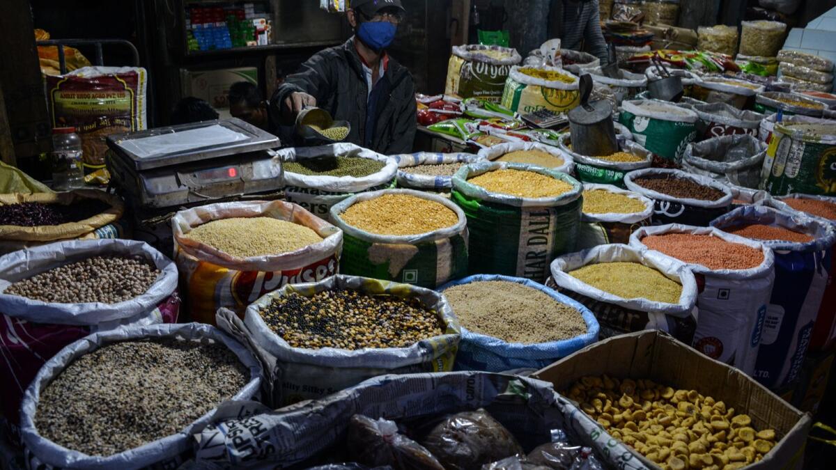 A vendor weighs pulses at his stall in a market in Siliguri - AFP)