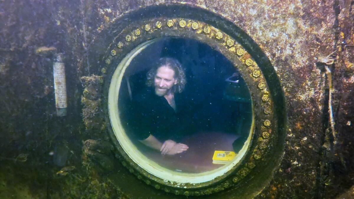 Diving explorer and medical researcher Dr Joseph Dituri peers out of a large porthole, on Saturday at Jules' Undersea Lodge positioned at the bottom of a 30-foot-deep lagoon in Key Largo, Florida.— AP