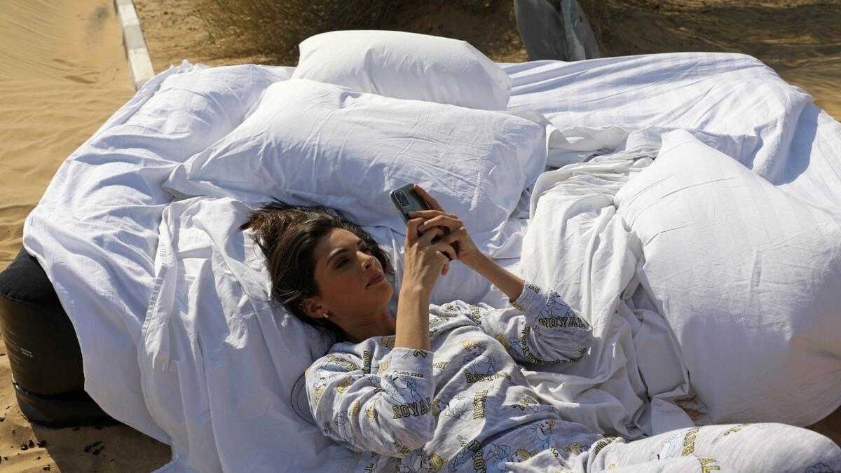 Israeli model May Tager uses her smartphone as she poses during the photoshoot.  Photo: Reuters