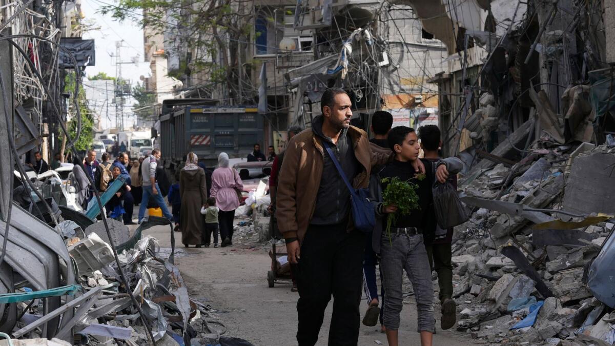 Palestinians walk by buildings destroyed in the Israeli bombardment of the Gaza Strip in Nusseirat refugee camp, central Gaza Strip. — AP