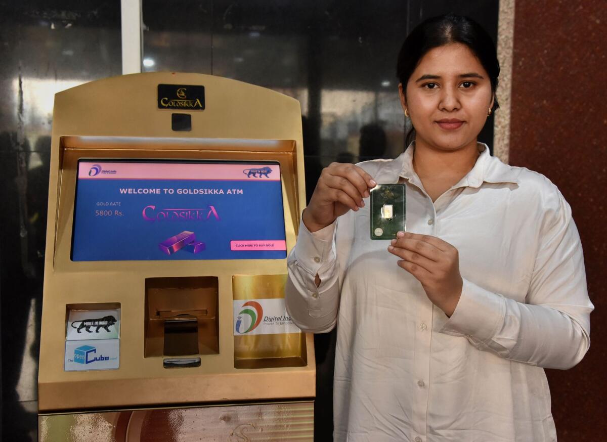 A woman poses for photos after withdrawing a gold coin from India's first Gold ATM in Hyderabad on Monday. — PTI