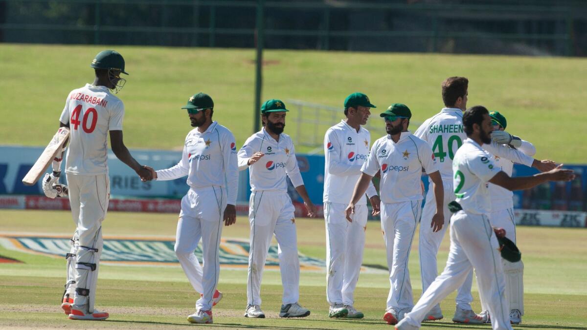 Babar Azam shakes hands with Blessing Muzarabani as other Pakistani players celebrate at the end of their second Test against Zimbabwe at Harare Sports Club. — AP