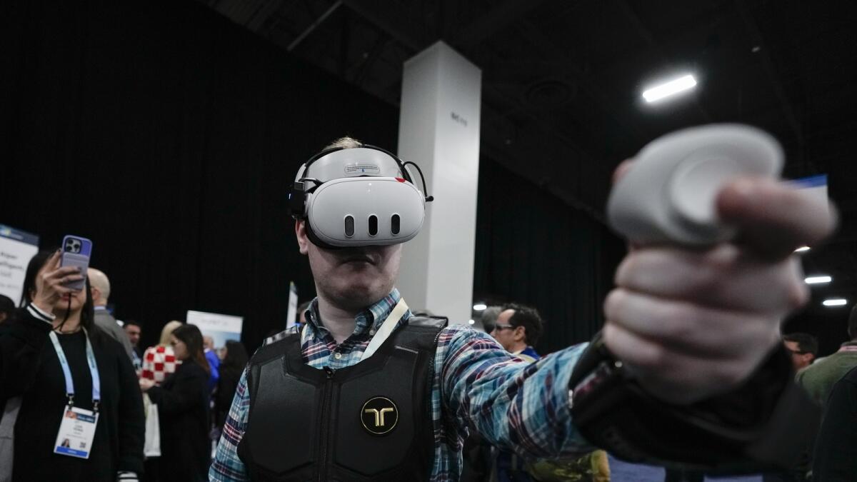 An attendee uses the bHaptics haptic vest,  designed to be used in tandem with augmented reality systems to provide haptic feedback in video games. — AP