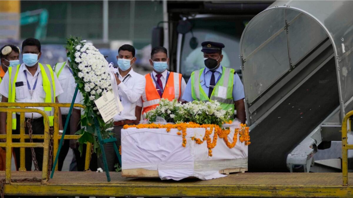 Sri Lankan airport workers stand next to a casket carrying remains of a Sri Lankan manager who was lynched by a mob in Sialkot. — AP file