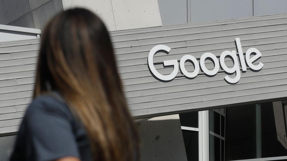 A woman walks below a Google sign on the campus in Mountain View, California. In results announced on Tuesday, Google's digital advertising empire is regaining the momentum it lost during the pandemic's early stages. And its YouTube video service is maturing into a major marketing magnet and companies are anticipating more spending by cooped-up consumers when the economy reopens. — AP
