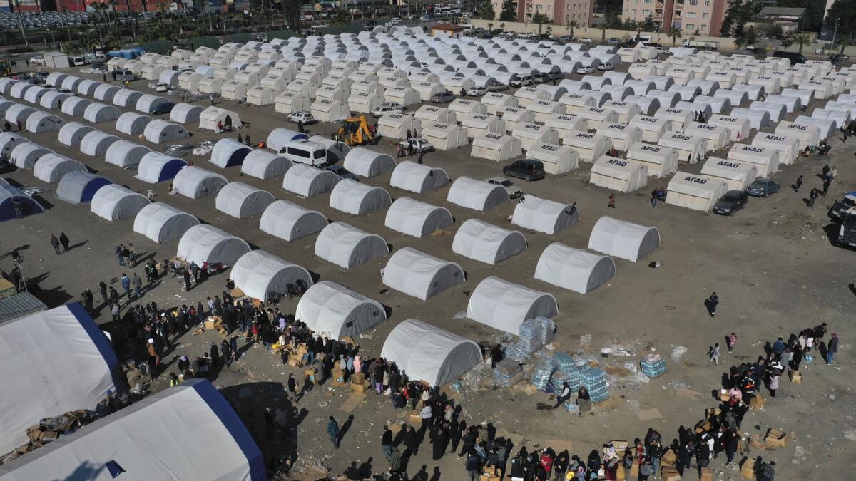 People who lost their houses in the devastating earthquake lineup to receive aid supplies at a makeshift camp in Iskenderun city, southern Turkey, on February 14, 2023. — AP