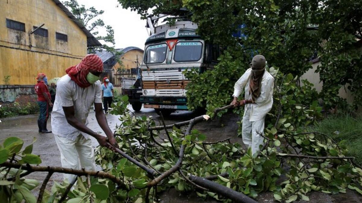 Rescue workers cut tree branches that fell on a truck trailer after heavy winds caused by Cyclone Amphan, in Kolkata, India, May 20. REUTERS/Rupak De Chowdhuri