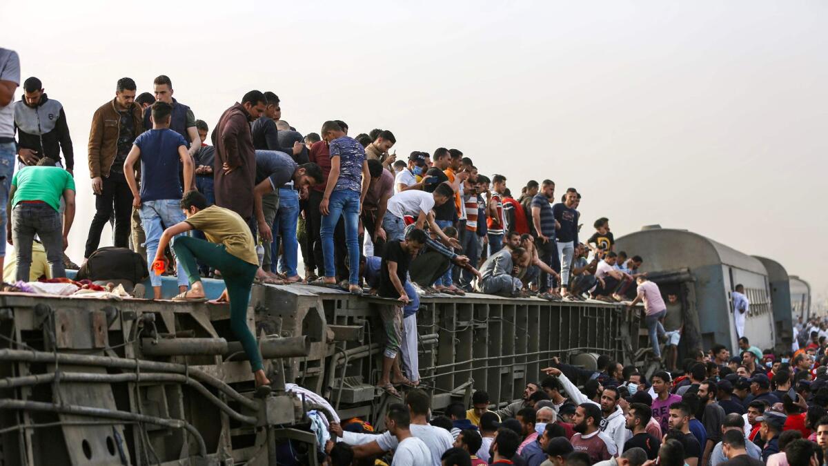 People climb an overturned train carriage as they gather at the scene of a railway accident in the city of Toukh in Egypt's central Nile Delta province of Qalyubiya on Sunday.
