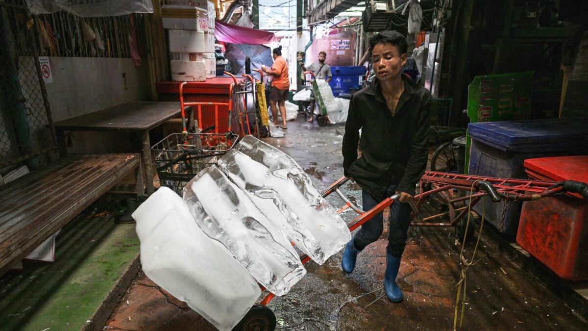 A worker transports blocks of ice through a fresh market on a hot day in Bangkok last week. Photo: AFP