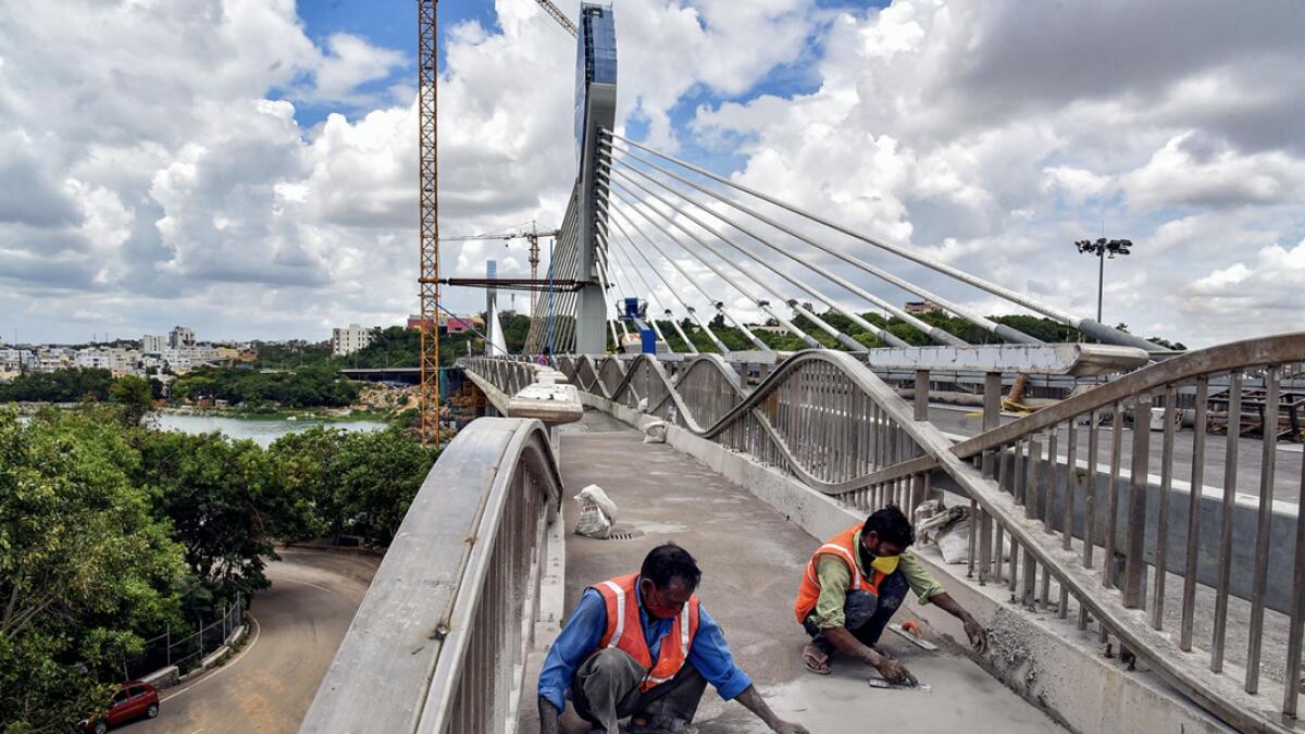 Labourers work to complete a cable-stayed bridge, during Unlock 2.0, at Durgam Cheruvu in Hyderabad, India. The bridge would cut short the distance between Jubilee hills and Madhapur. Photo: PTI