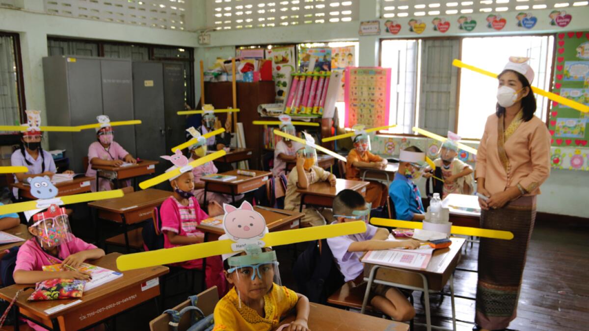 A teacher and students in protective gear wear special hats for social distancing to help curb the spread of the coronavirus at Ban Pa Muad School in Chiang Mai north of Thailand. Photo: AP
