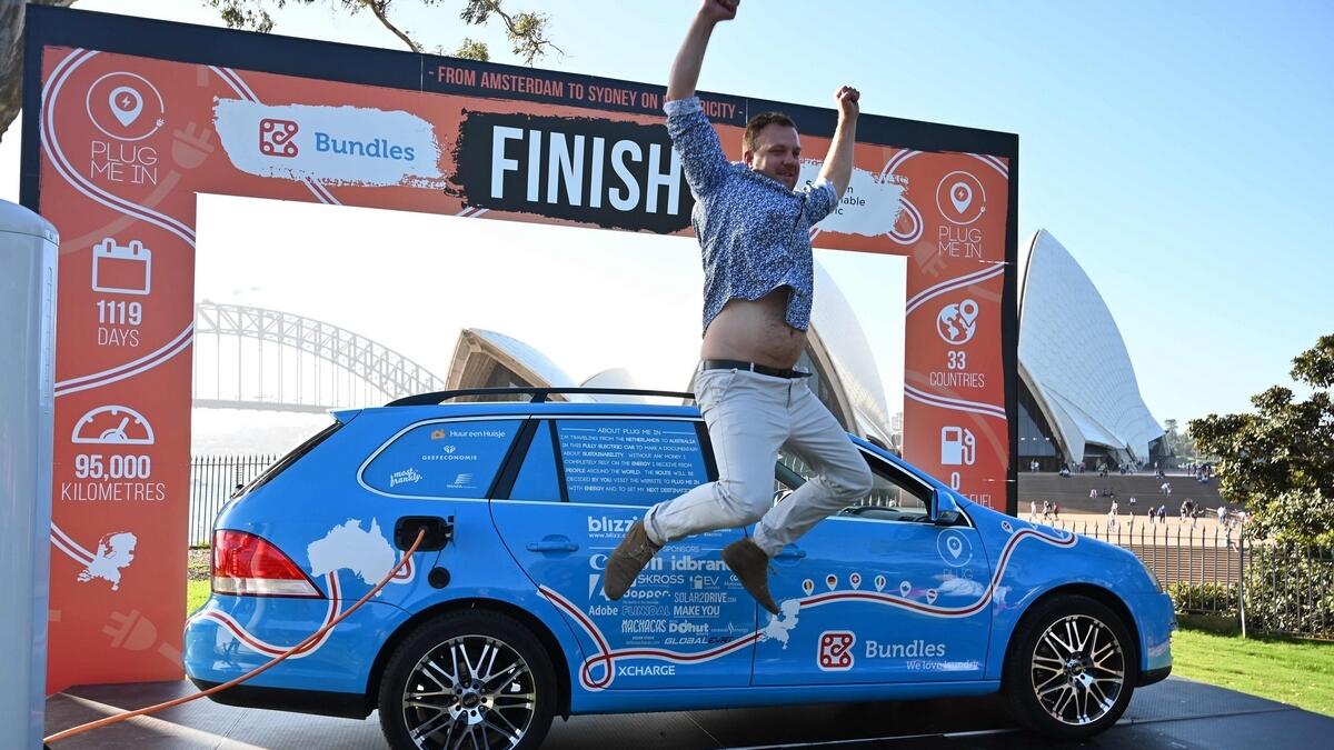Dutch driver Wiebe Wakker (C) celebrates after driving his retrofitted station wagon nicknamed 'The Blue Bandit' onto a platform to complete a round-an-world trip in an electric car.-AFP