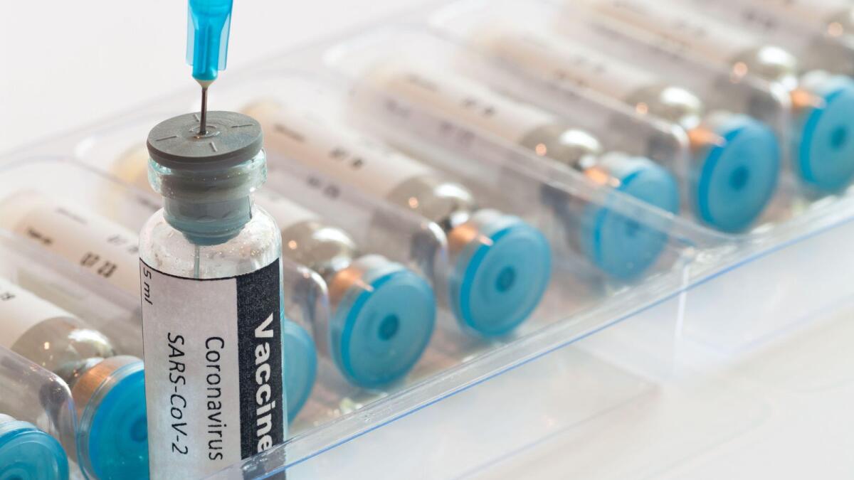 Medical syringe with glass ampoule vial with coronavirus COVID-19 vaccine.