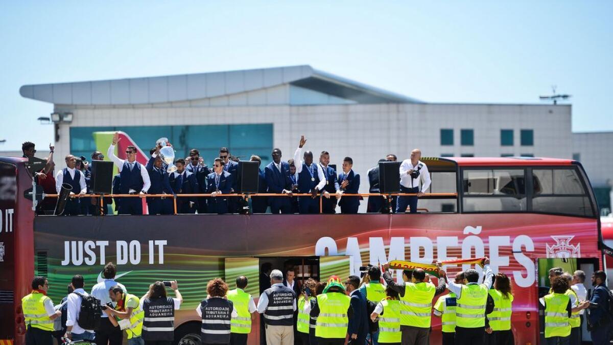 Airport workers welcome Portugal's national football team members riding on an open top bus after their arrival at Lisbon airport on Monday.