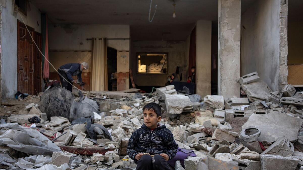 A Palestinian boy sits on the rubble of a destroyed building after an Israeli strike in Rafah. — AP