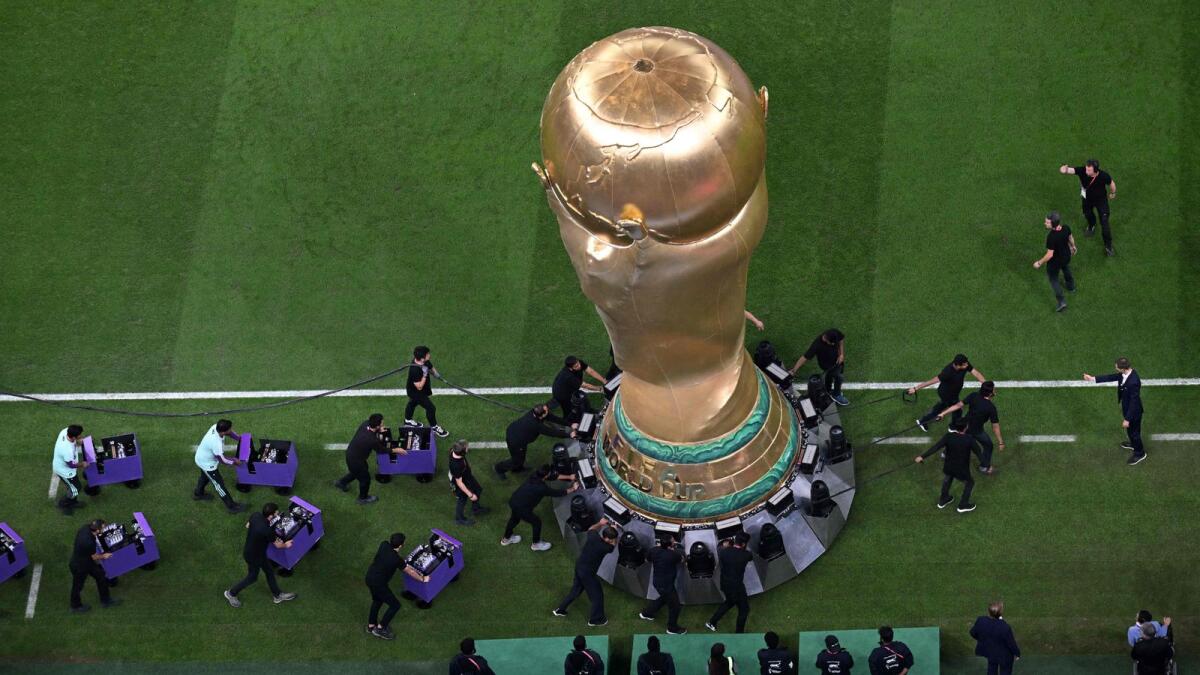 Stadium volunteers bring a giant replica of the World Cup trophy on the pitch before the start of the Qatar 2022 World Cup football semi-final match between Argentina and Croatia at Lusail Stadium in Lusail, north of Doha on December 13, 2022. — AFP