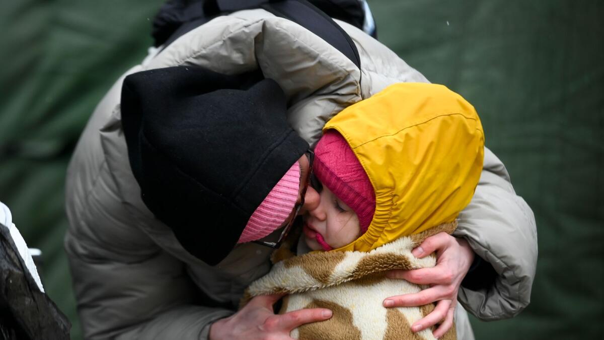 A woman, who fled Ukraine, comforts a girl wrapped in a blanket after crossing the Moldova-Ukrainian border's checkpoint near the town of Palanca on March 2, 2022. (Photo: AFP)
