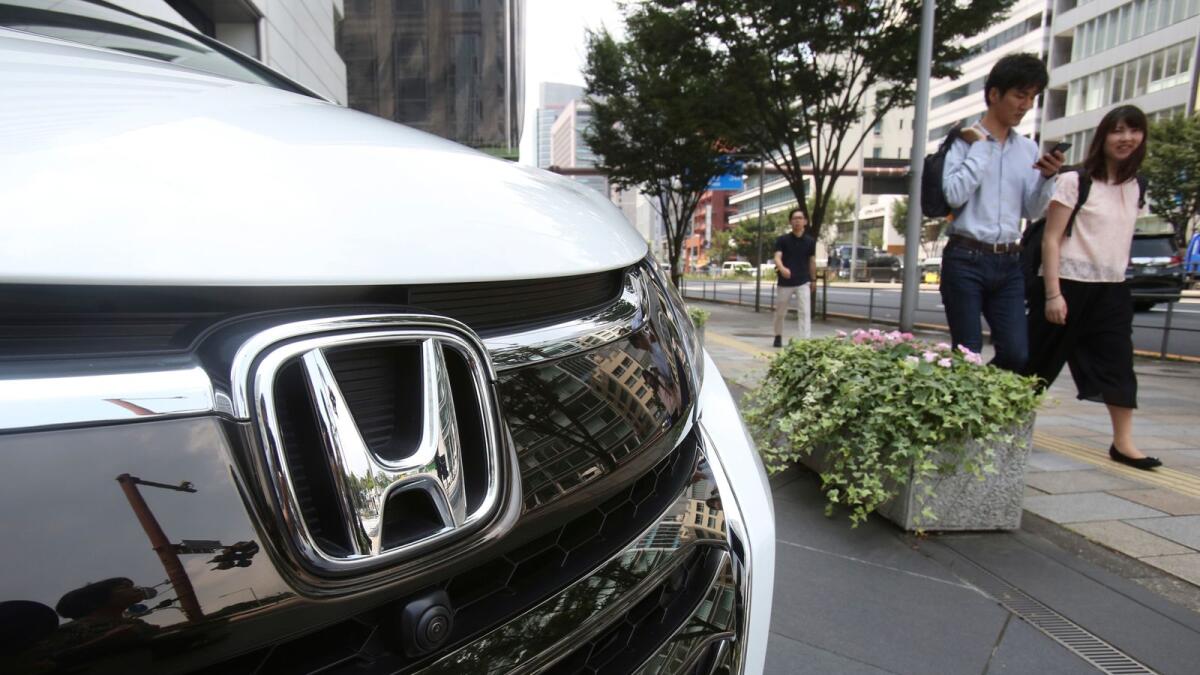 People walk past a Honda car on display at Honda Motor Company headquarters in Tokyo. — AP file photo