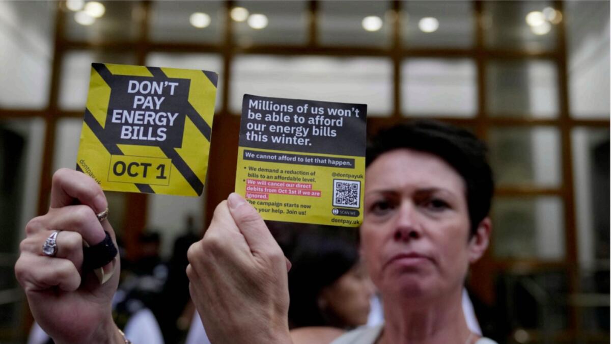 A demonstrator holds up two cards as they protest outside the British energy regulator Ofgem. — AP