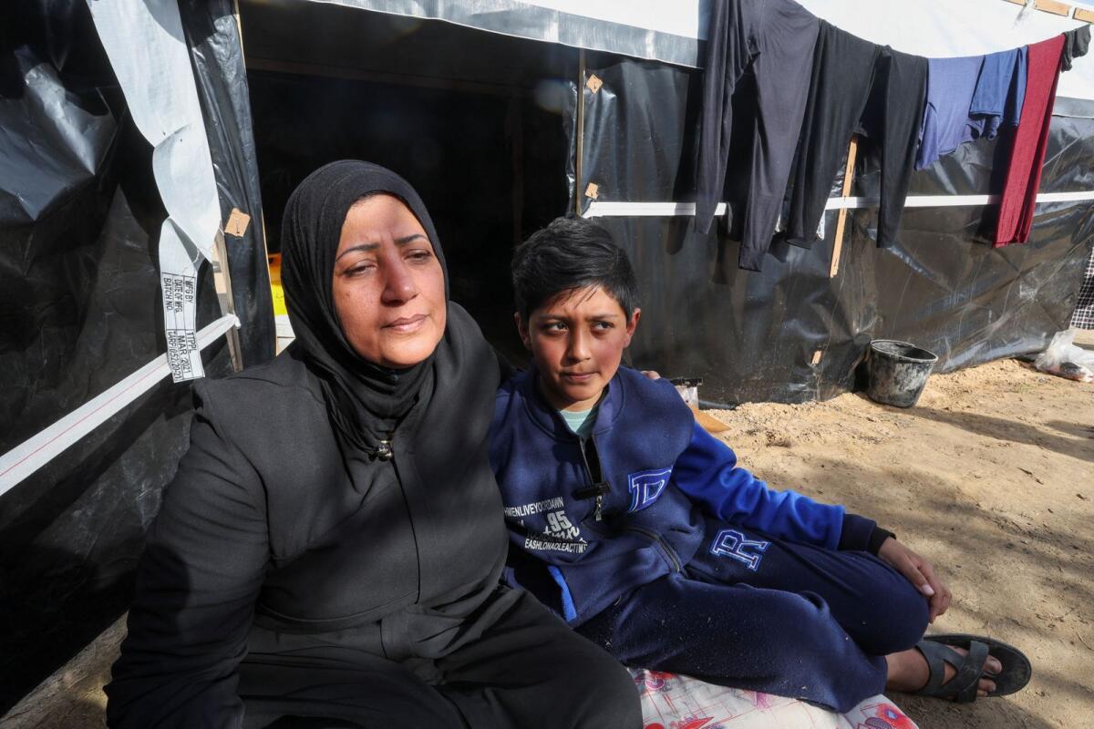 Ahmed Jarbou, a displaced Palestinian boy whose father was killed in an Israeli missile strike, sits next to his mother outside their makeshift shelter in Rafah in the southern Gaza Strip, on January 8, 2024. — Reuters