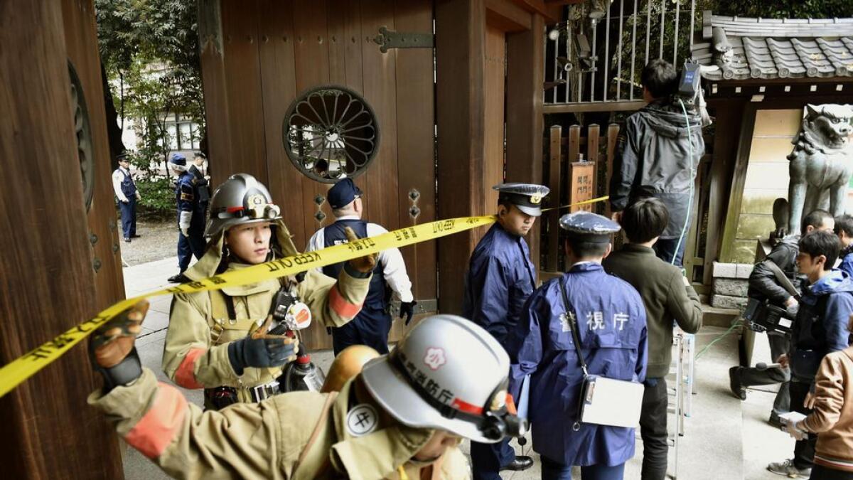 Firefighters and police officers inspect around the south gate of Yasukuni shrine in Tokyo.