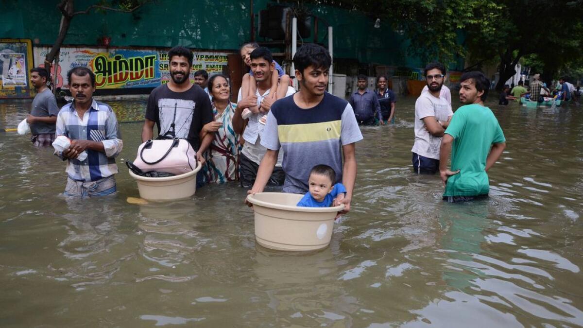 Indian residents carry children and possessions as they walk through floodwaters in Chennai.