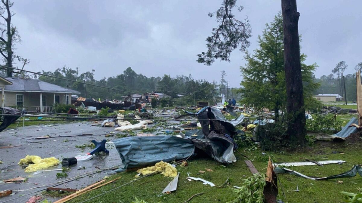 Debris covers a street in East Brewton, Alabama after a suspected tornado spurred by Tropical Storm Claudette demolished or badly damaged at least 50 homes. A multi-vehicle crash, likely occurred due to the storm, killed 10 people including nine children. — AP