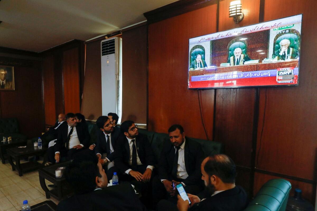 Lawyers, some of them look on television screen, dispaying the live broadcast of the proceeding from the Supreme Court of Pakistan, at the Sindh High Court Bar Association in Karachi on Monday. — reuters