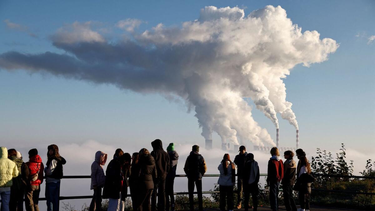 People watch smoke and steam billow from Belchatow Power Station, Europe's largest coal-fired power plant powered by lignite, in Zlobnica, Poland. - Reuters file