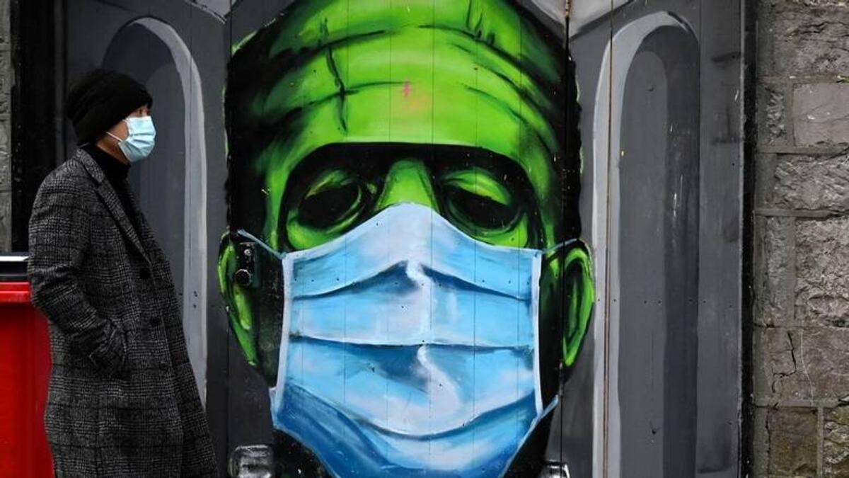 A man walks past a graffiti of a Frankenstein wearing a protective face mask on a doorway amid the spread of the Covid-19 pandemic, in Galway, Ireland. — Reuters file