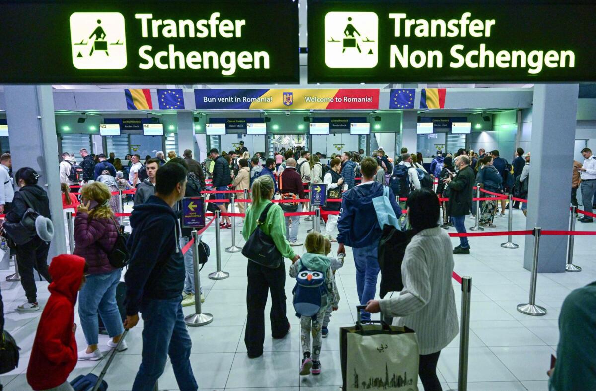 Travelers walk next to newly installed signs pointing to Schengen and non-Schengen areas minutes after midnight, just after Romania's official entry into the European area of free circulation at Otopeni's 'Henri Coanda' international airport on March 31, 2024. — AFP