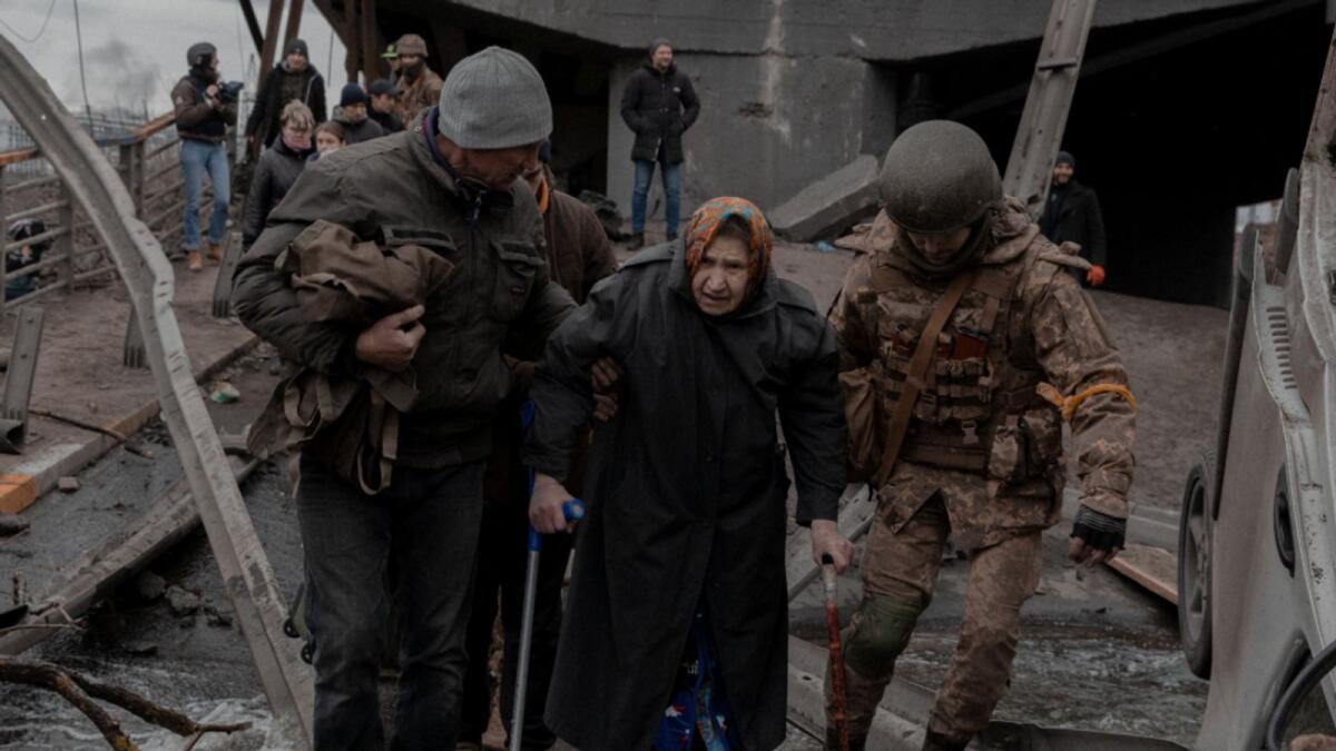 An elderly woman is helped while crossing a destroyed bridge as she tries to leave the city of Irpin, in the Kyiv region, Ukraine March 5, 2022. Photo: Reuters