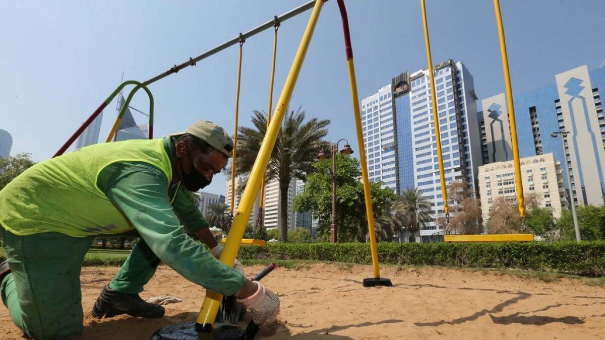 A worker paints the newly installed swing in a play area in Abu Dhabi. -Photo by Ryan Lim/Khaleej Times